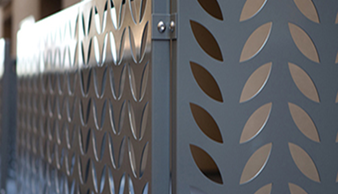 A metal fence with a pattern of leaves on it.