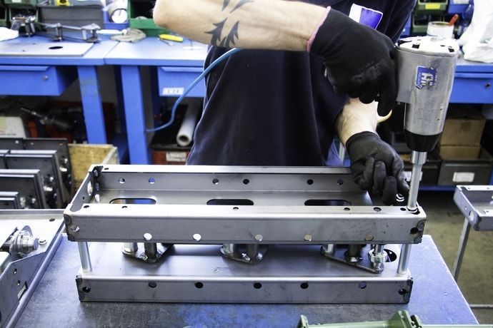 A man is working on a piece of metal in a factory.