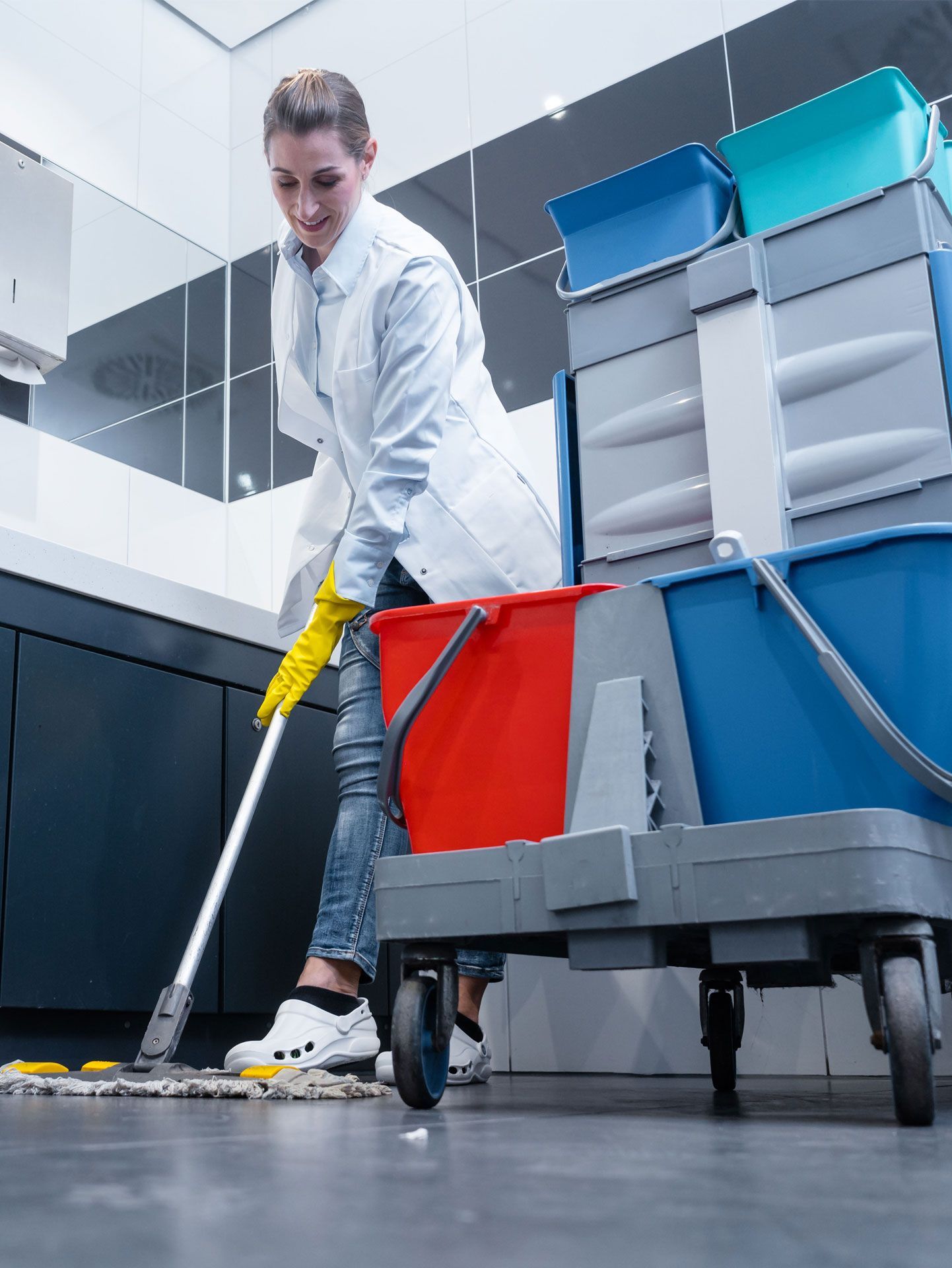 a woman is cleaning a bathroom floor with a mop and buckets