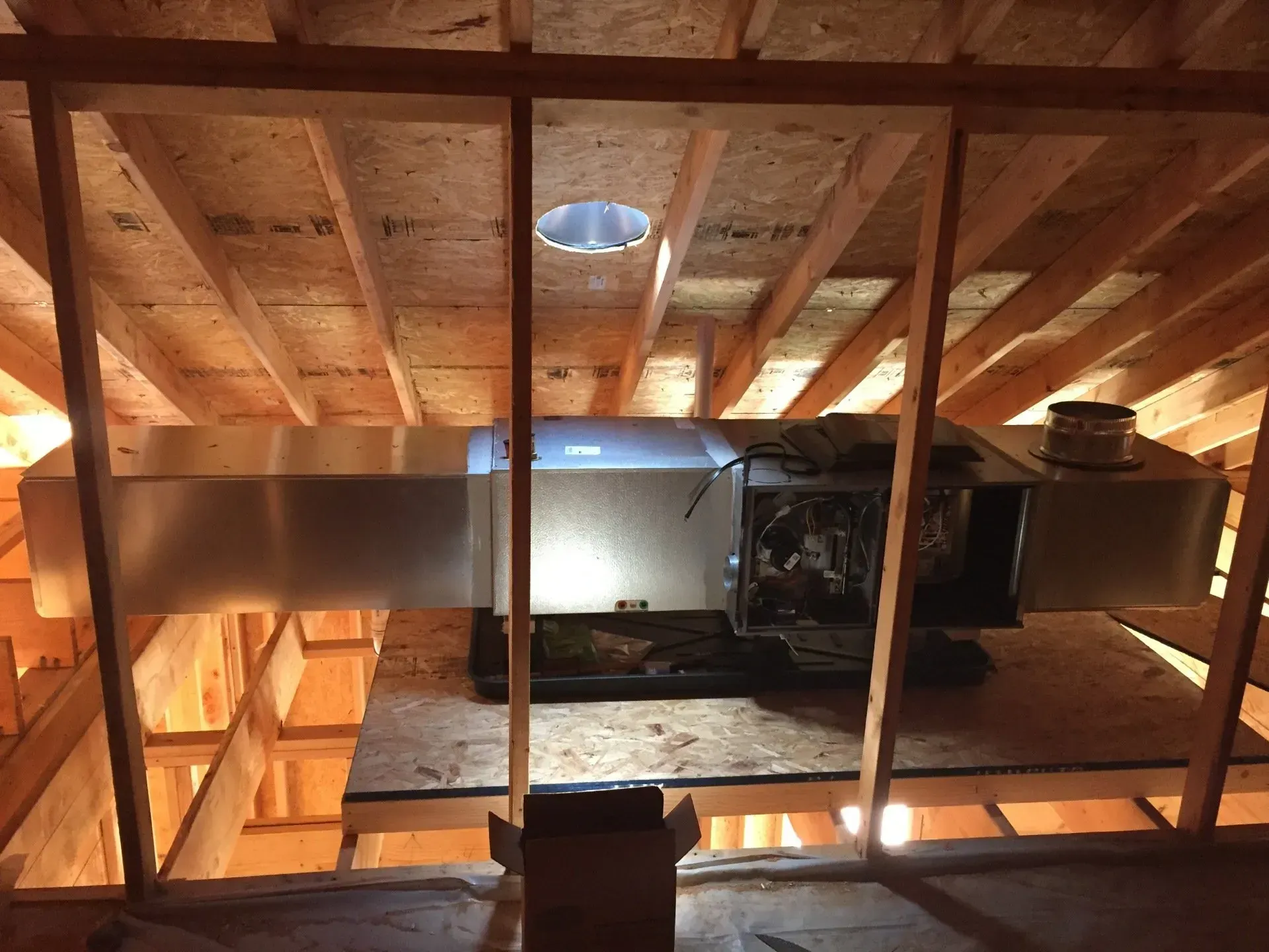 Attic interior with exposed wooden beams, a skylight, and construction materials under renovation