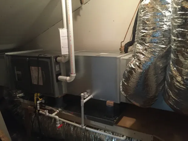 Basement HVAC system with ductwork and insulated pipes beneath a sloped ceiling