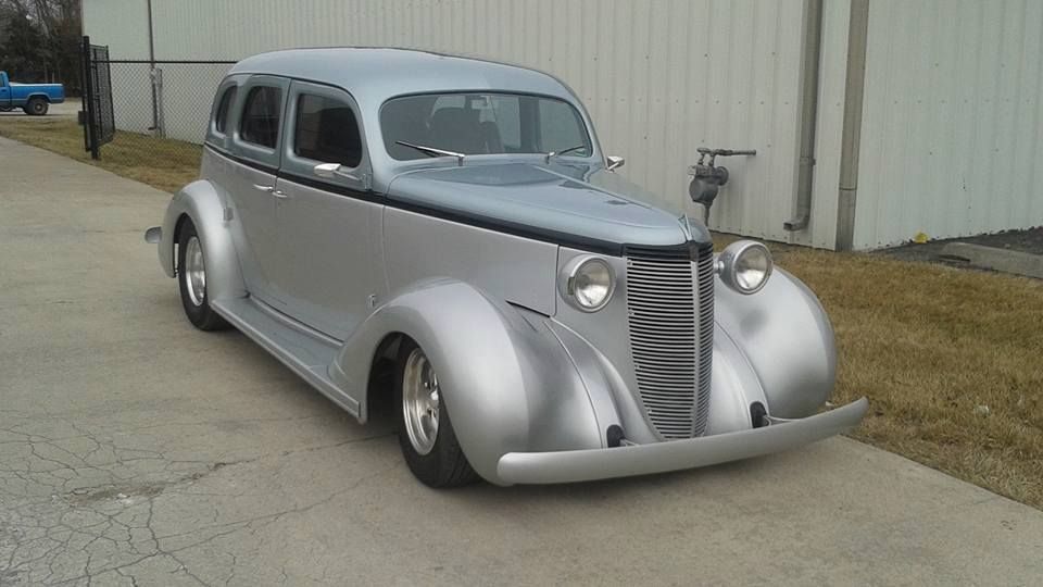 Silver vintage coupe parked outside a beige building, shown from the front-left angle