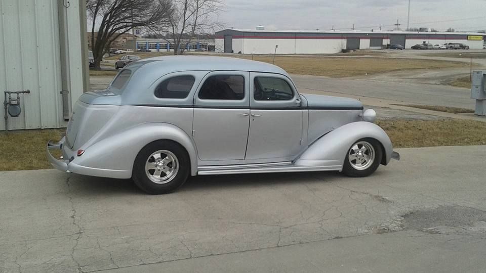 Silver vintage coupe parked on a driveway beside a building