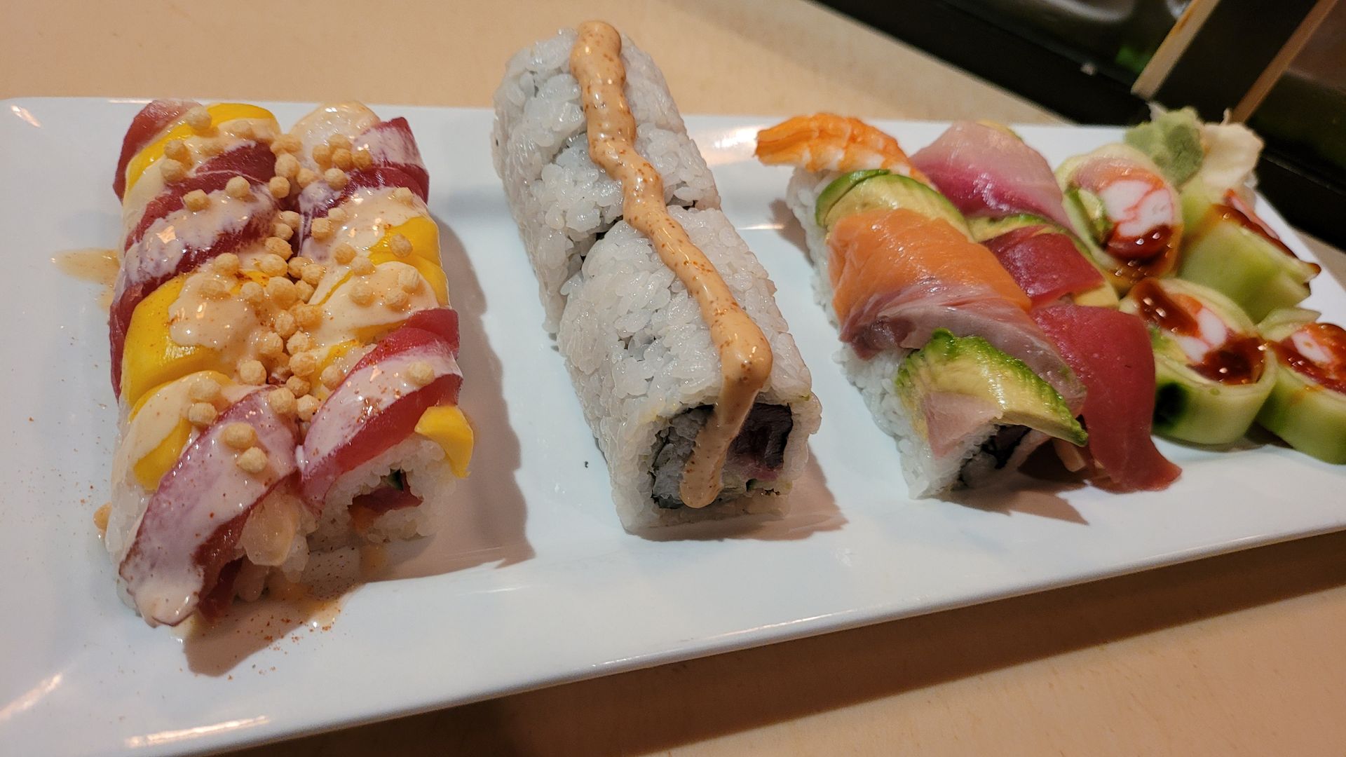 A white plate topped with sushi and fried shrimp