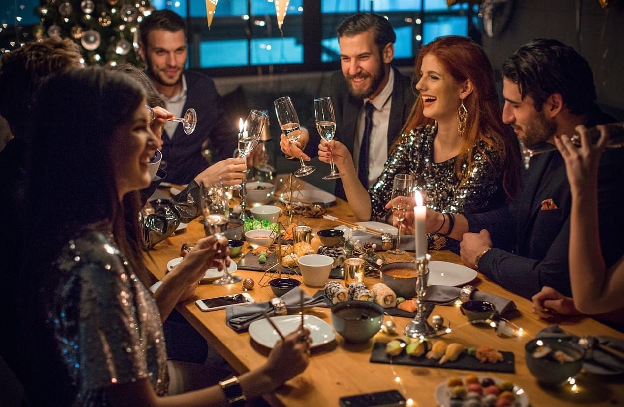 A group of people are sitting at a table eating food and drinking wine.