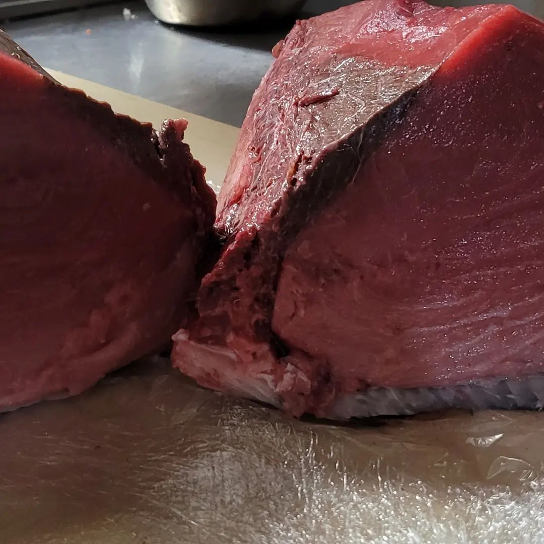 A piece of meat is cut in half on a cutting board