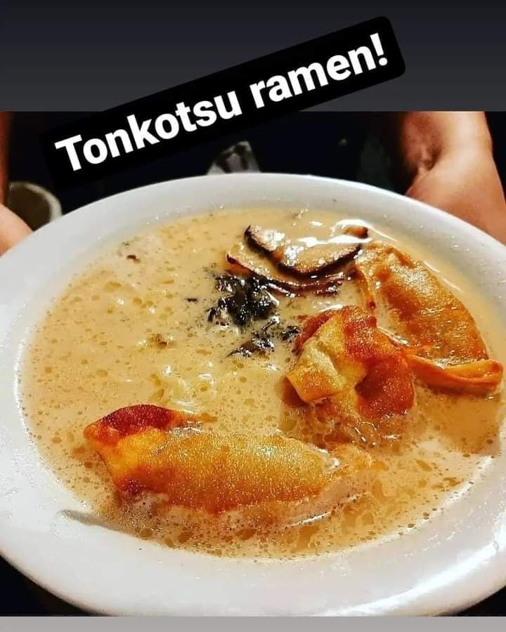 A person is holding a bowl of tonkotsu ramen