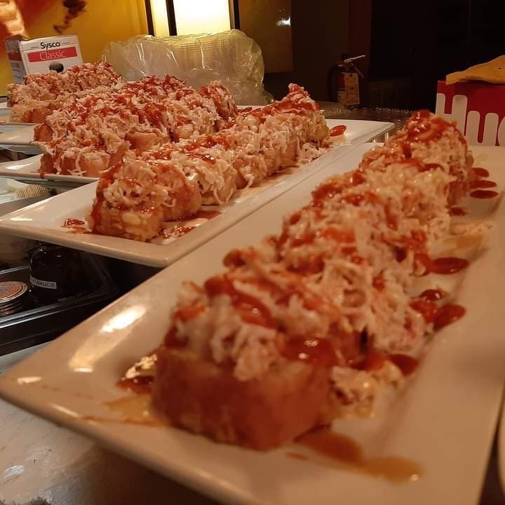 Several plates of food are lined up on a table and one of the plates has a red sauce on it