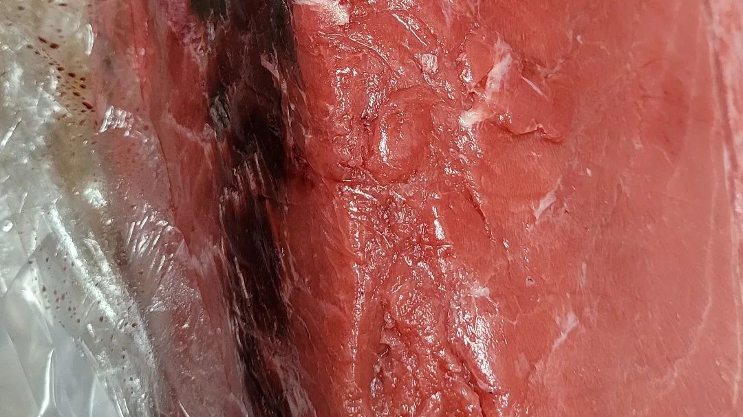 A close up of a piece of red meat wrapped in plastic.