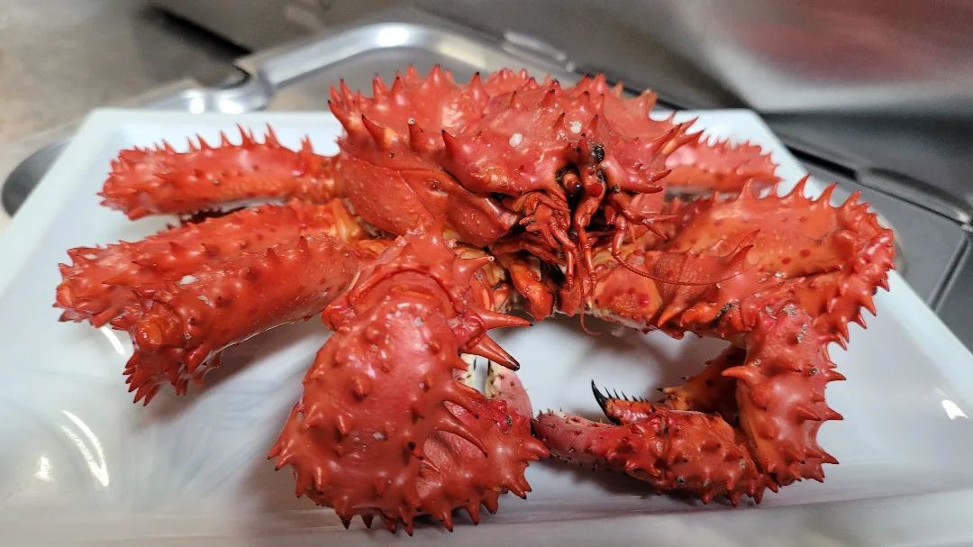 A close up of a red crab on a white plate.