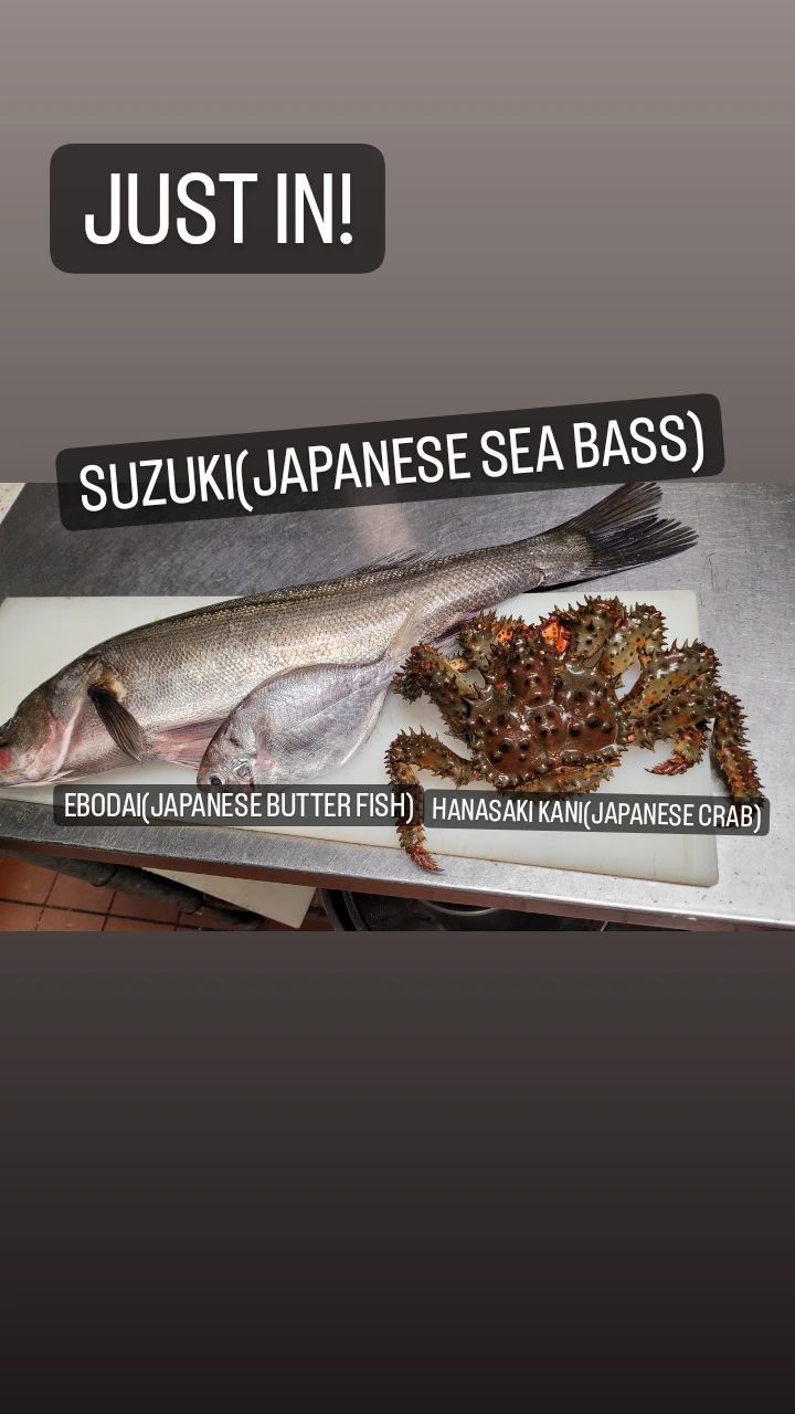 A suzuki japanese sea bass and a crab are on a cutting board.
