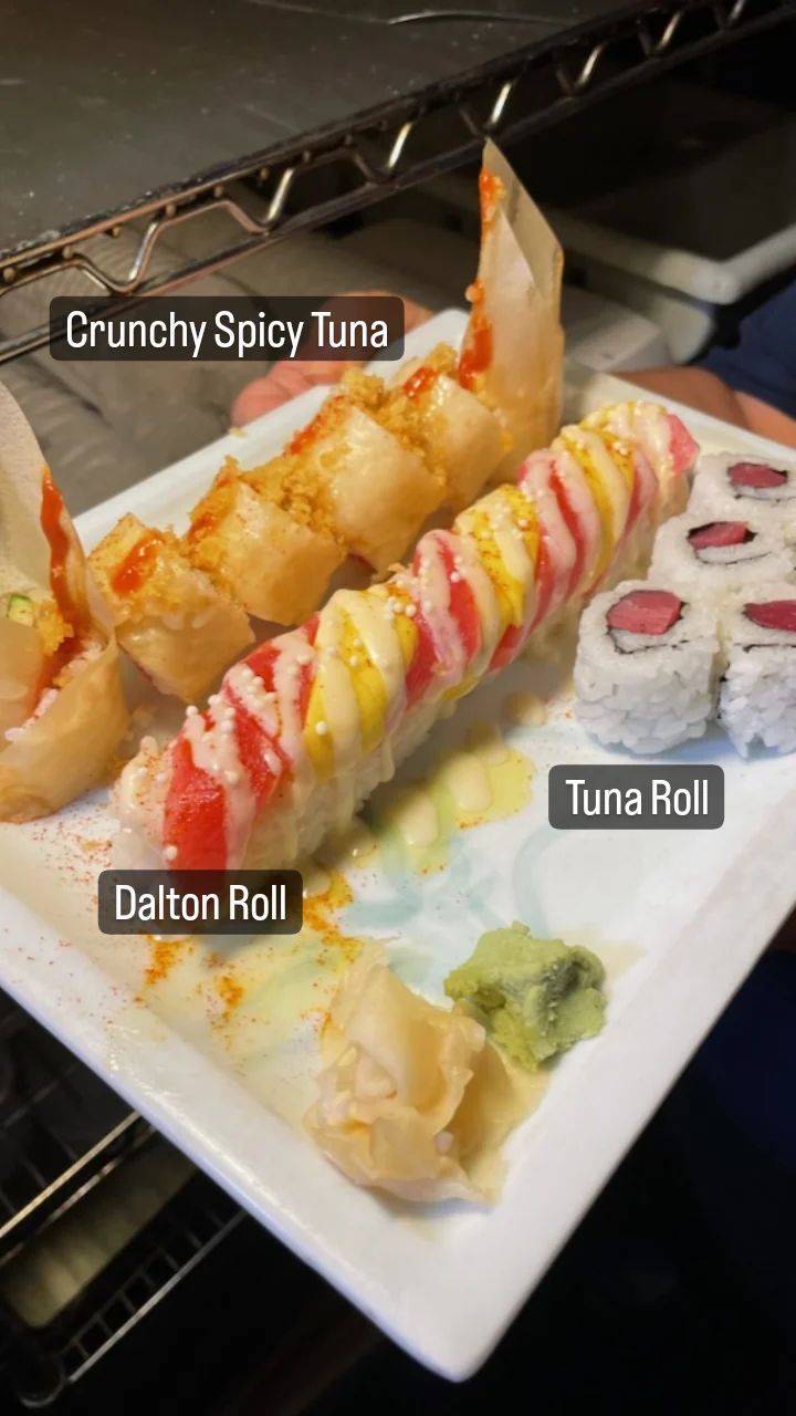A white plate topped with sushi rolls and a crunchy spicy tuna roll.