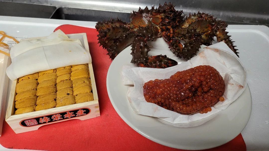 A plate of food and a box of food are on a table.