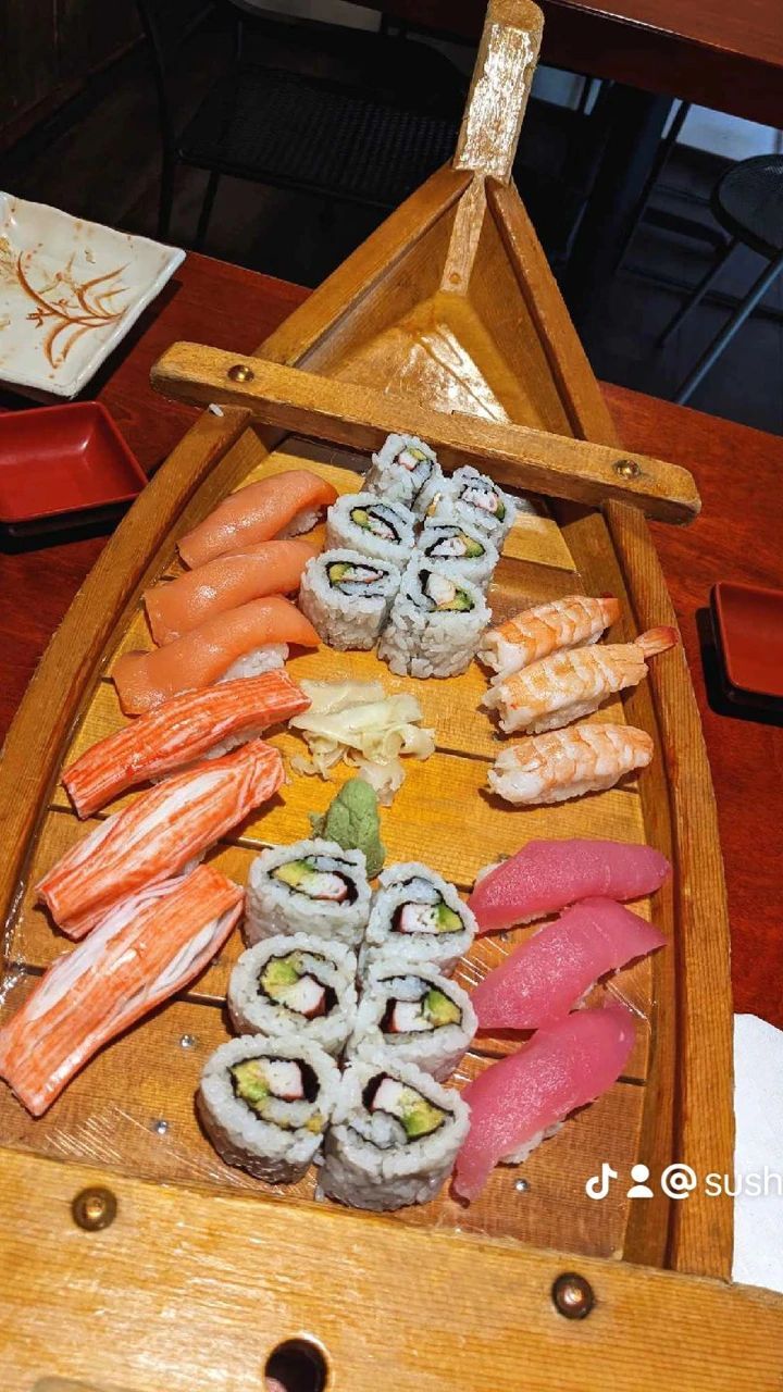 A wooden boat filled with sushi and crab sticks on a table.