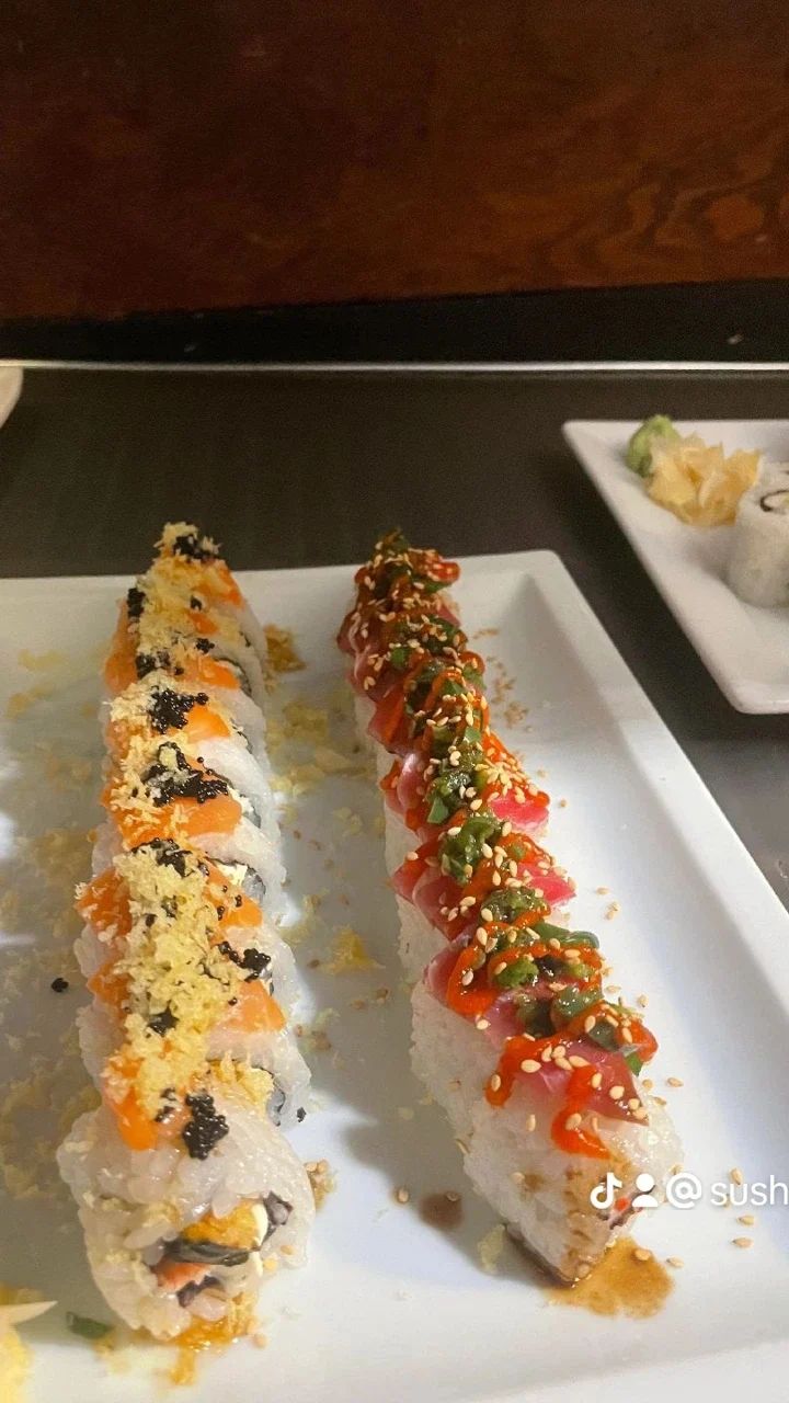 Two rolls of sushi are on a white plate on a table.