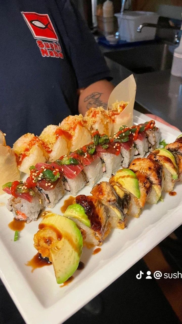 A person is holding a plate of sushi on a table.