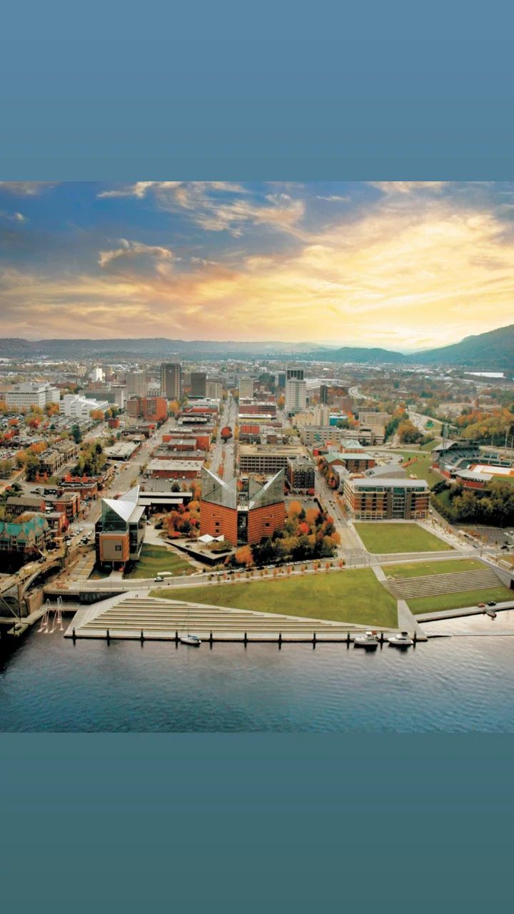 An aerial view of a city next to a body of water at sunset.