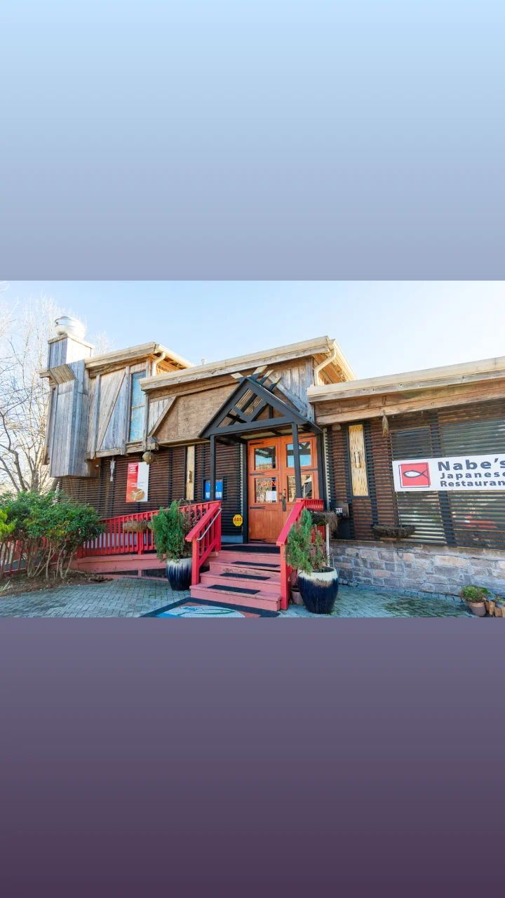 A large wooden house with a thatched roof and stairs leading up to it.