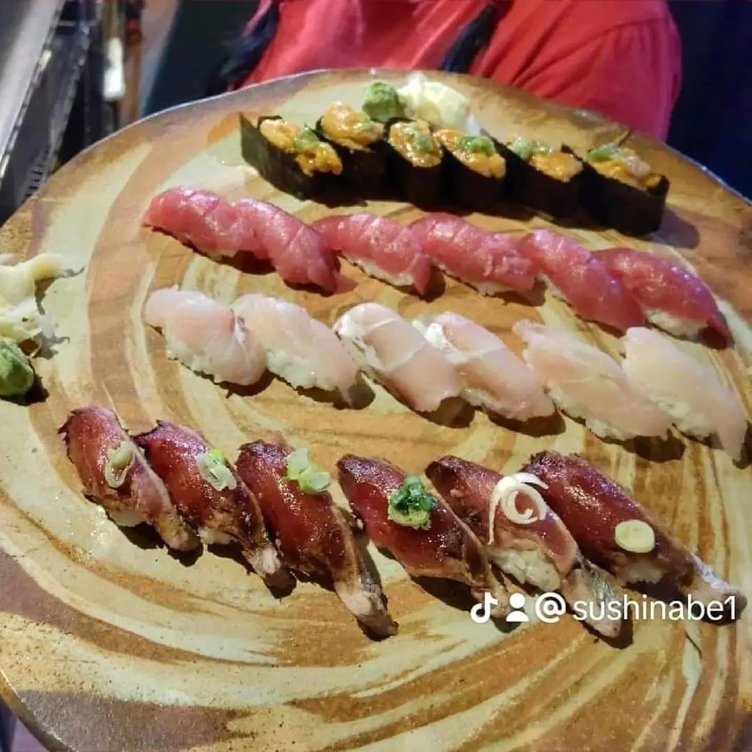 A person is holding a plate of sushi with a watermark that says sushinabet