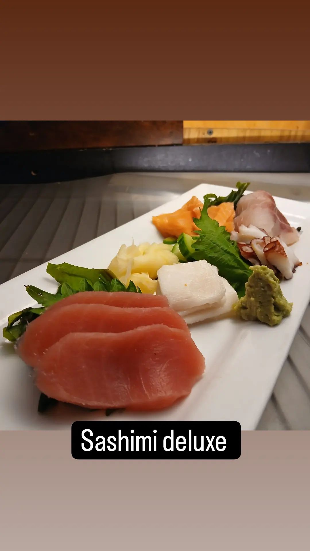 A close up of a plate of sashimi deluxe on a table.