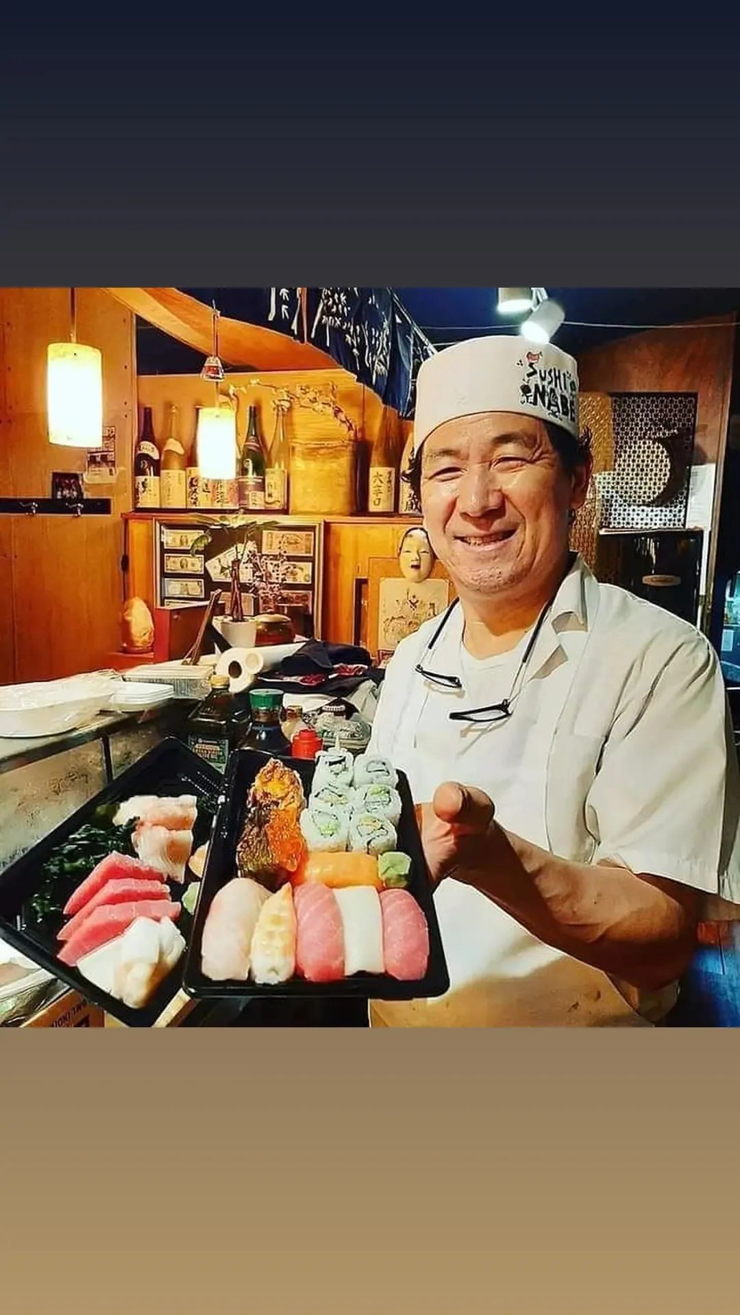 A man is holding a plate of sushi in a restaurant.