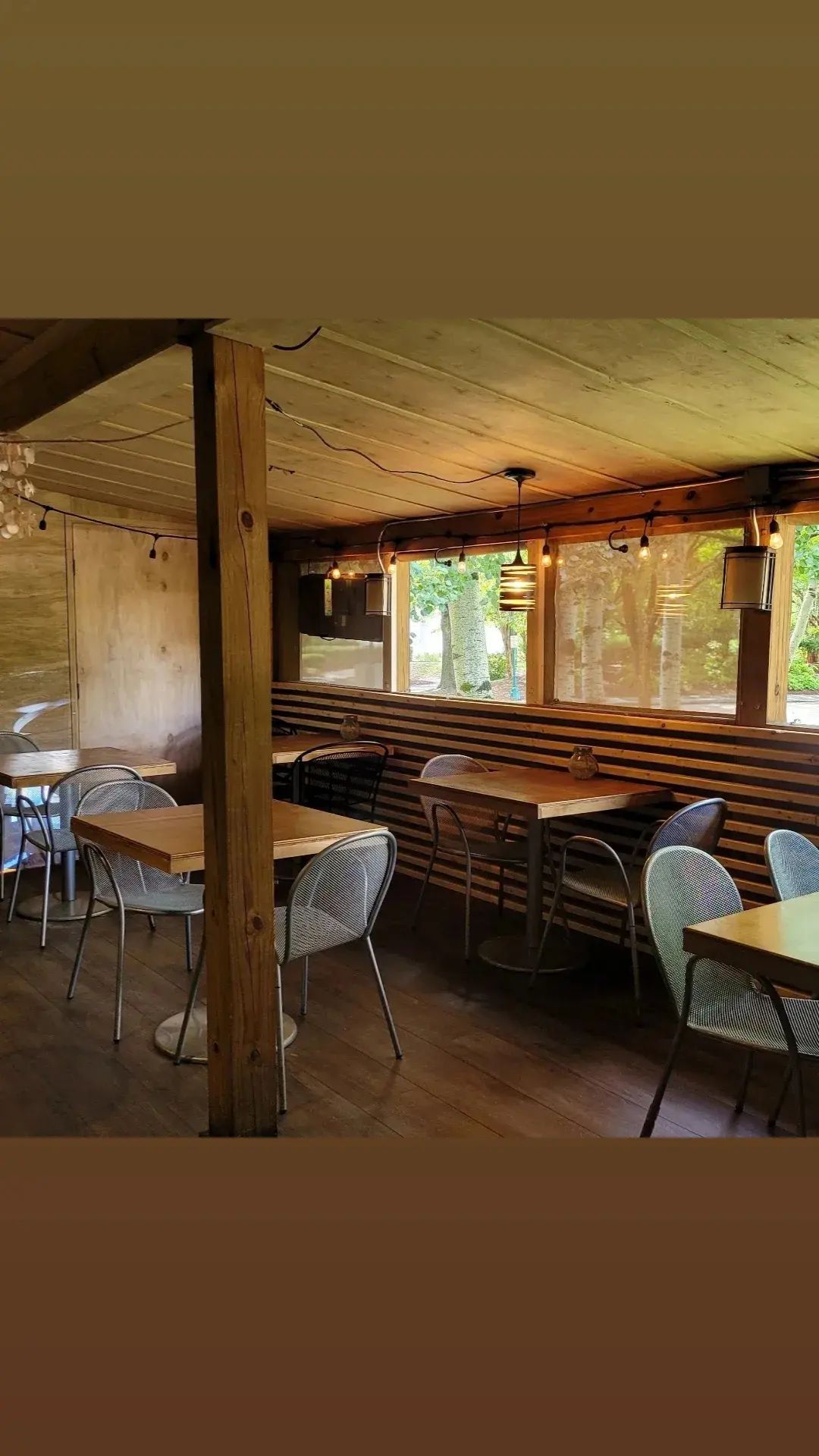 A restaurant with tables and chairs and a wooden wall.