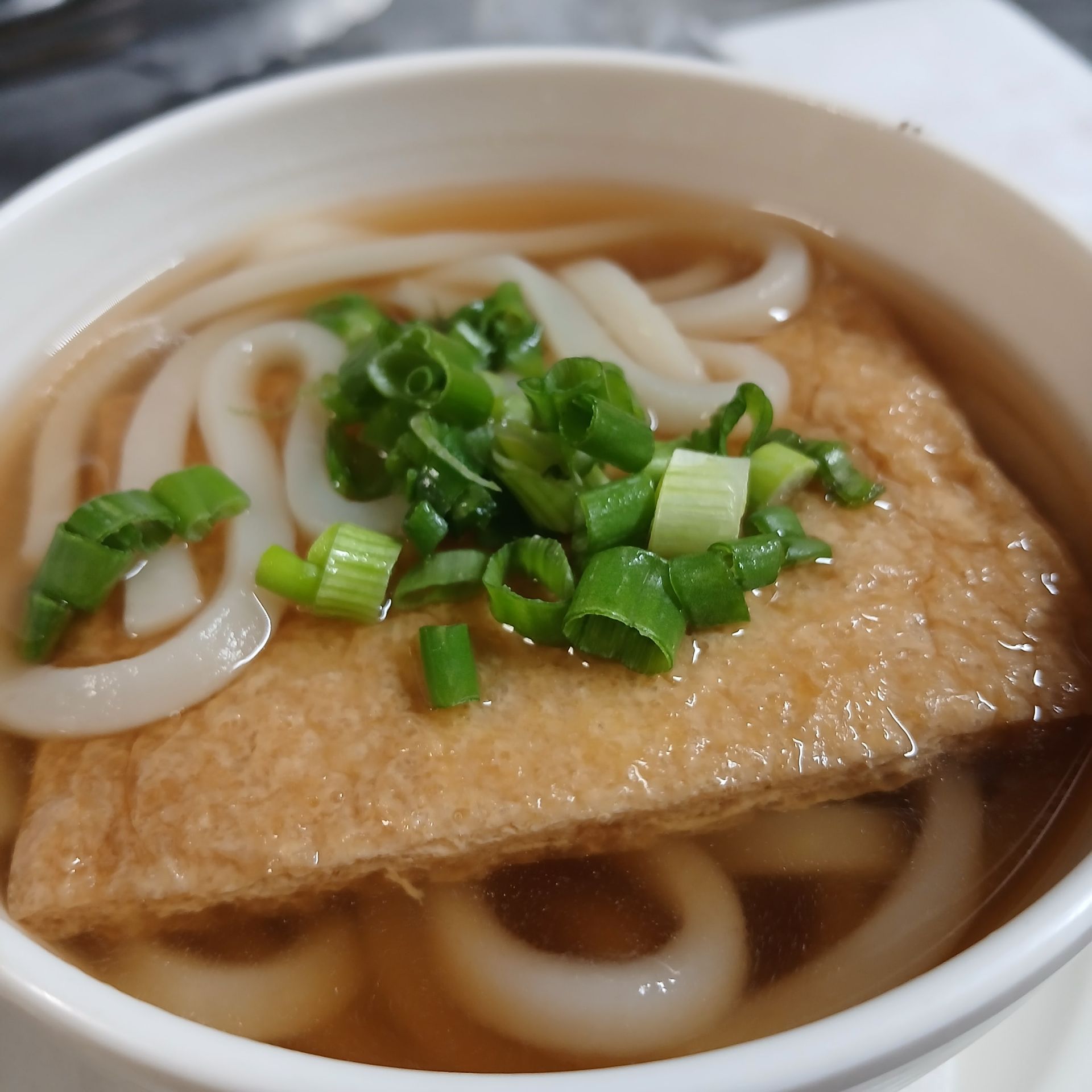 A bowl of soup with noodles and green onions on top