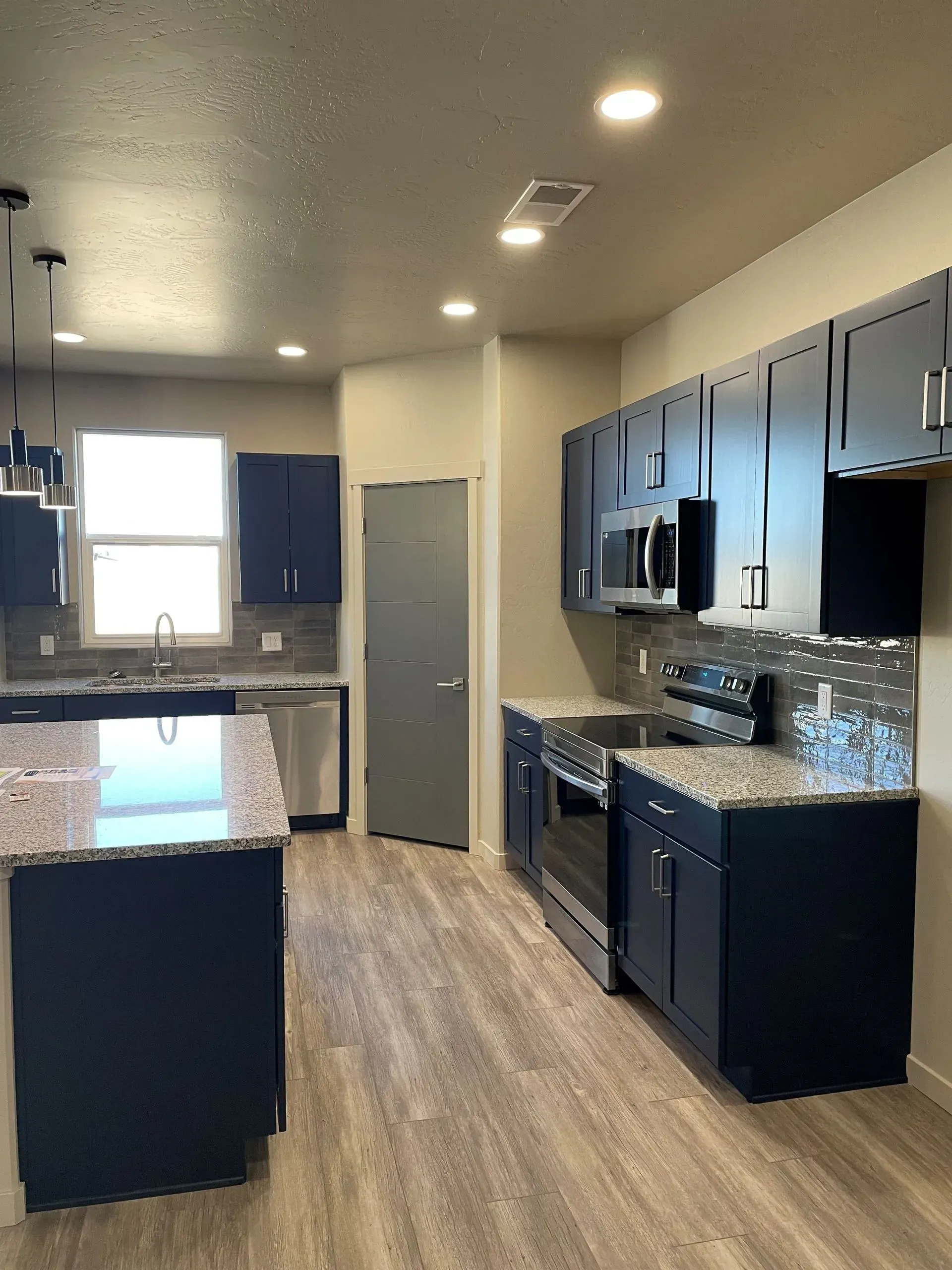 Modern kitchen with navy cabinets, granite countertops, and stainless steel appliances.