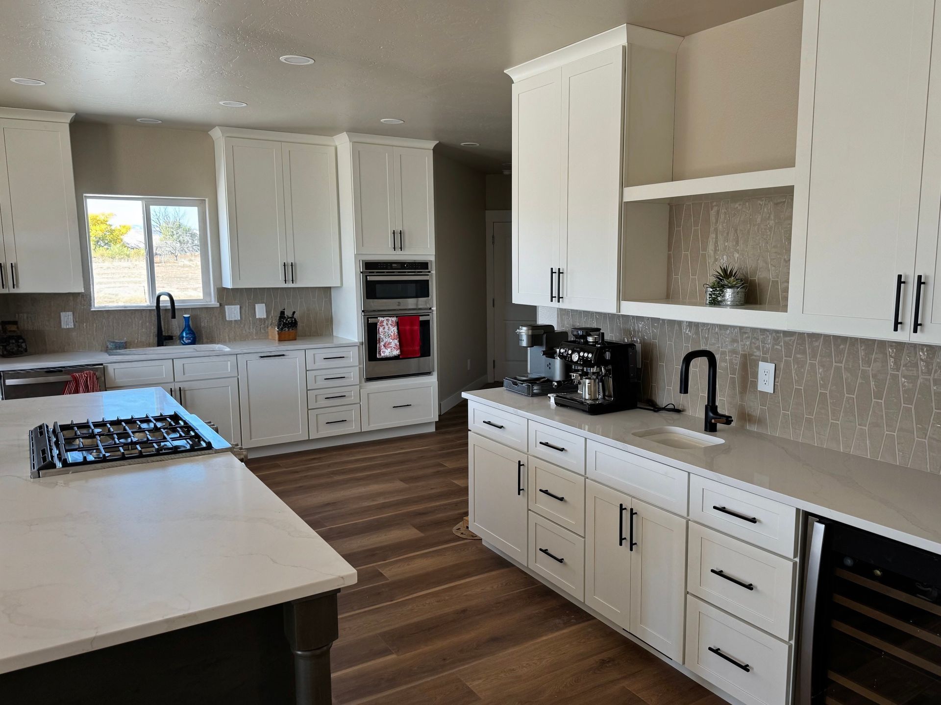 Modern white kitchen with island, cabinets, appliances, and dark fixtures.