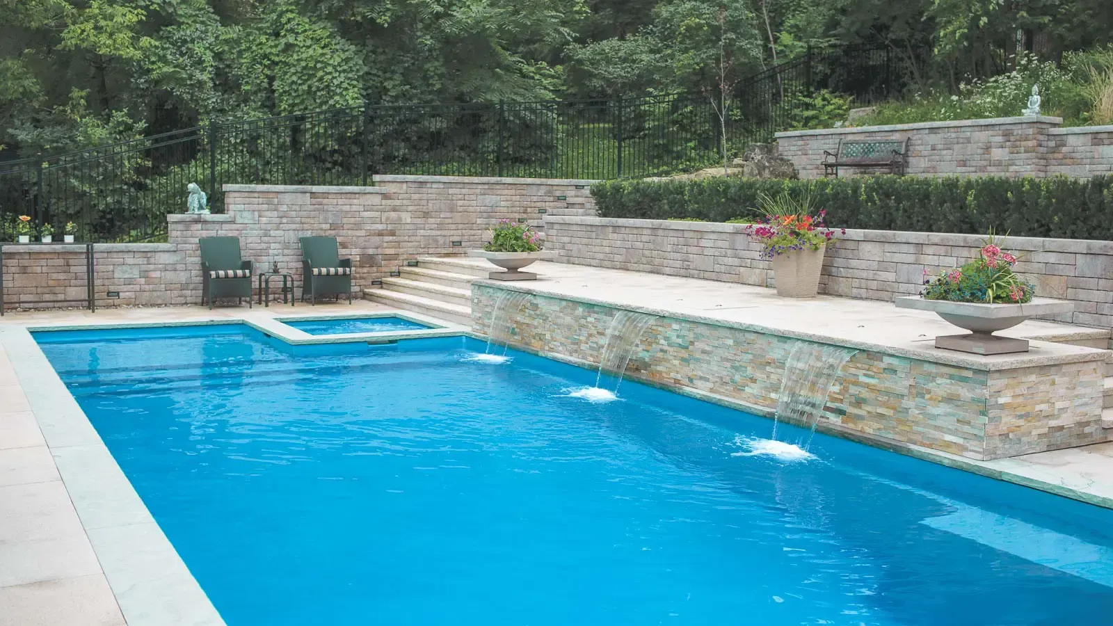 Outdoor swimming pool with bright blue water beside a stone patio and garden seating area