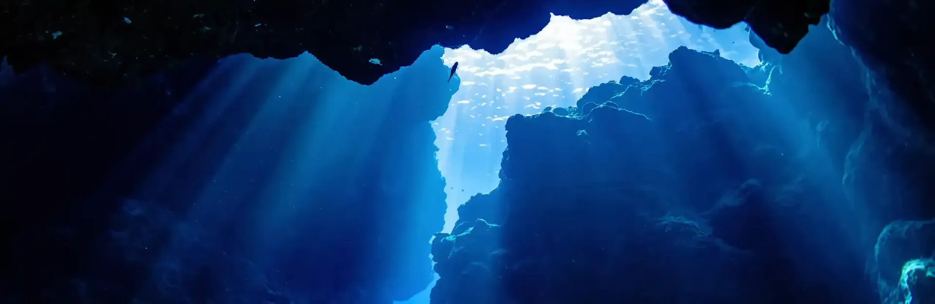 Sunbeams shining through blue underwater cave openings
