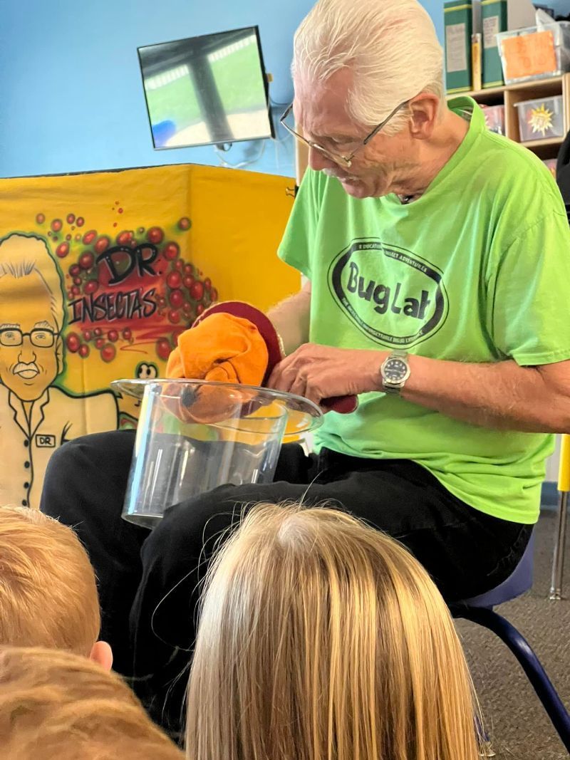 A man in a green shirt is sitting in front of a group of children.
