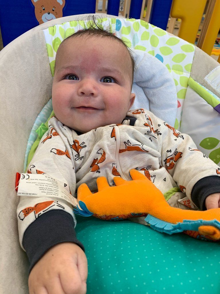 A baby is sitting in a high chair with a stuffed animal.