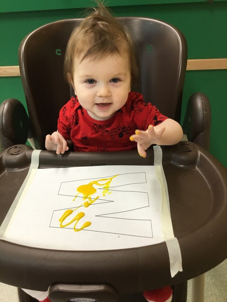 A baby is sitting in a high chair with a piece of paper on it.