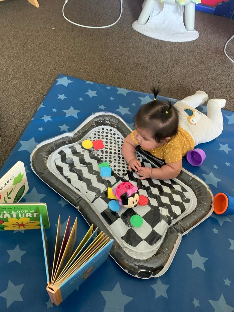 A baby is laying on a blue mat playing with toys.