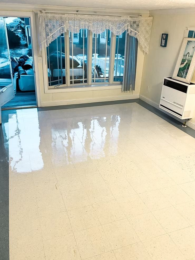 Empty bright room with glossy white floor, large windows, and a radiator on the right.