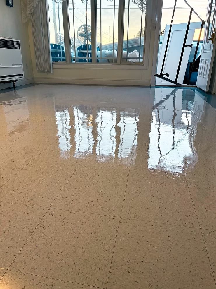 Polished terrazzo floor reflecting large glass doors and bright daylight in a room with patio furniture outside