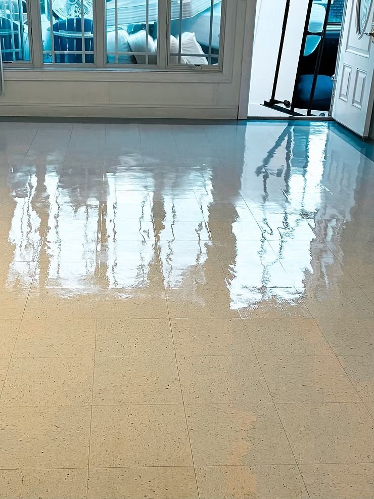 Shiny beige floor with reflections of windows in a bright room, near an open doorway.