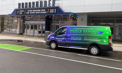 Green and purple service van parked outside a building entrance on a wet street
