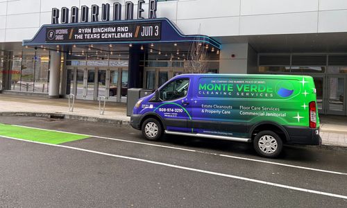 Green and purple service van parked outside a building entrance on a wet street