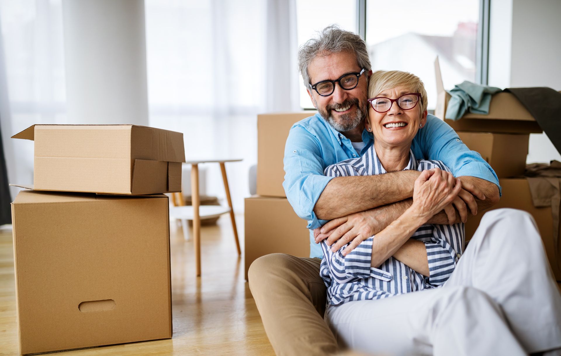 Mid shot of older couple hugging surrounded by boxes