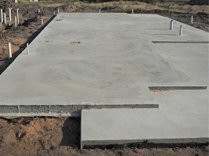 A large concrete slab is sitting on top of a dirt field.