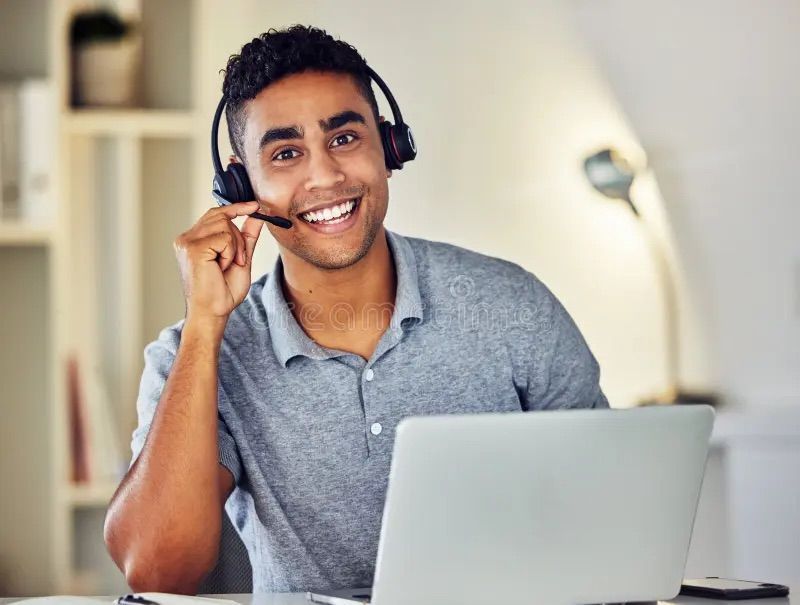 A man wearing a headset is sitting in front of a laptop computer.