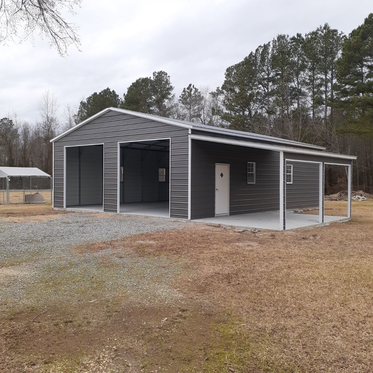 A large metal building with a porch and trees in the background