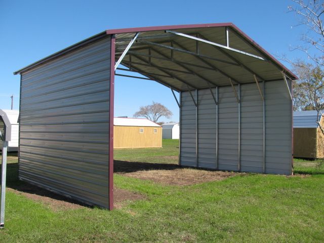 A metal shed is sitting in the middle of a grassy field.