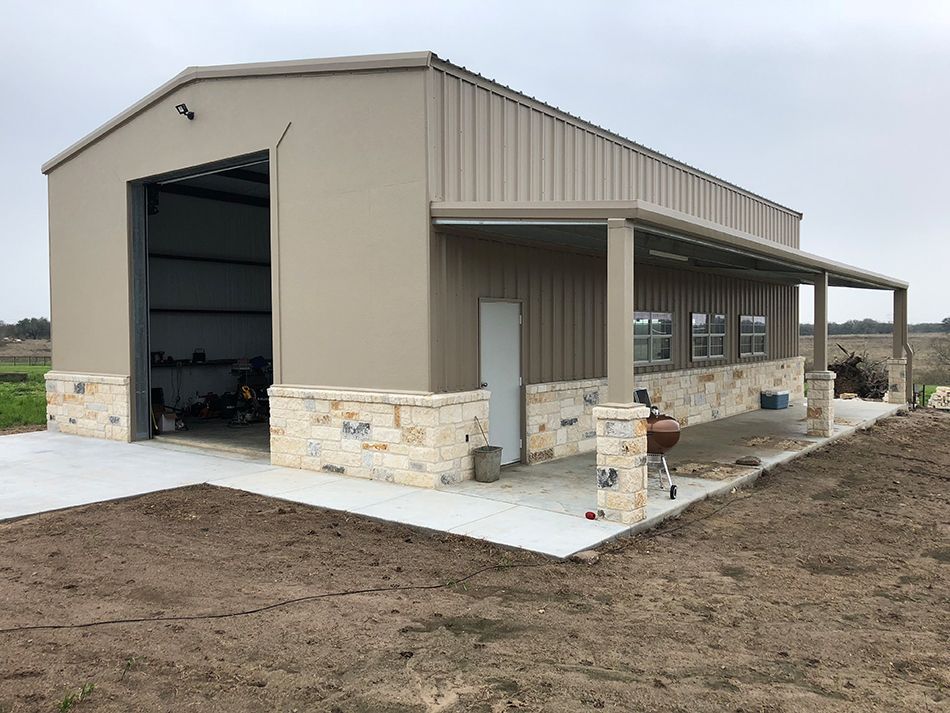 A large metal building with a large garage door and a porch.