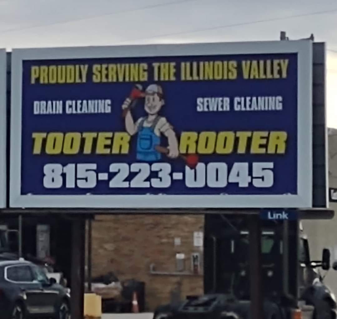 A billboard for Tooter Rooter drain and sewer cleaning services, showing a cartoon plumber and phone number 815-223-0045.