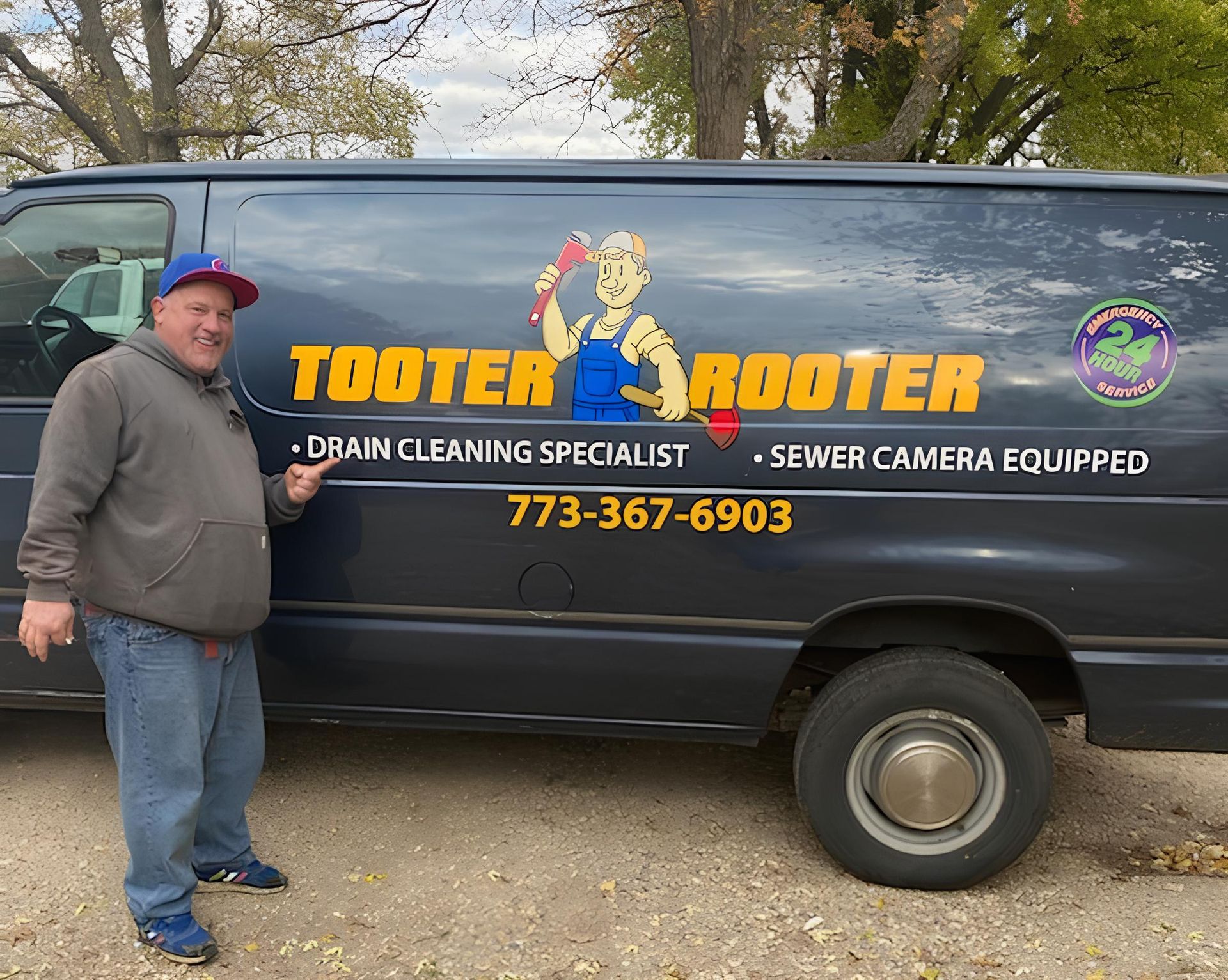 A person in a gray hoodie and blue cap points to a dark van branded Tooter Rooter with drain cleaning information.