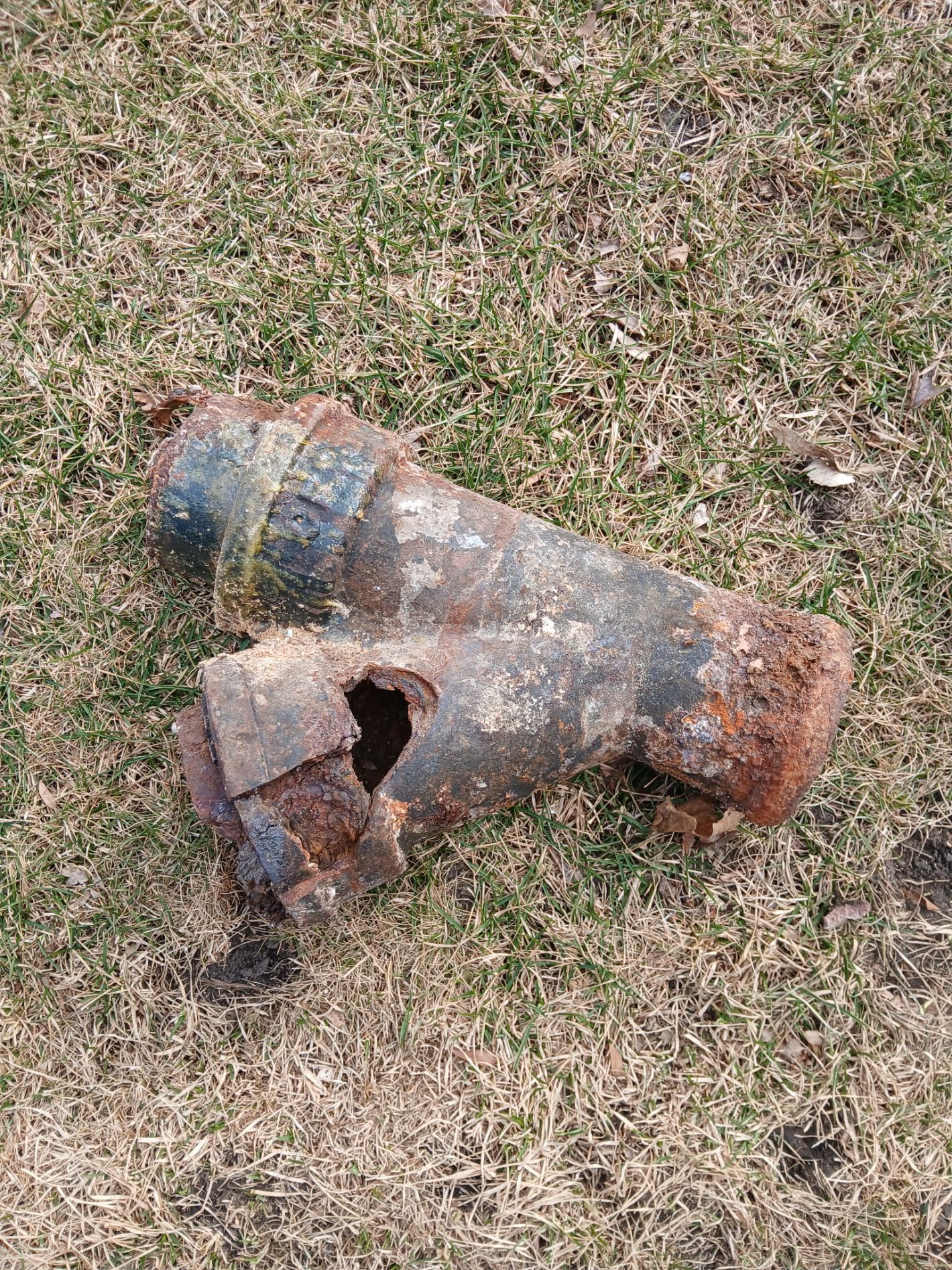 Rusty broken pipe or metal cylinder lying on dry grass