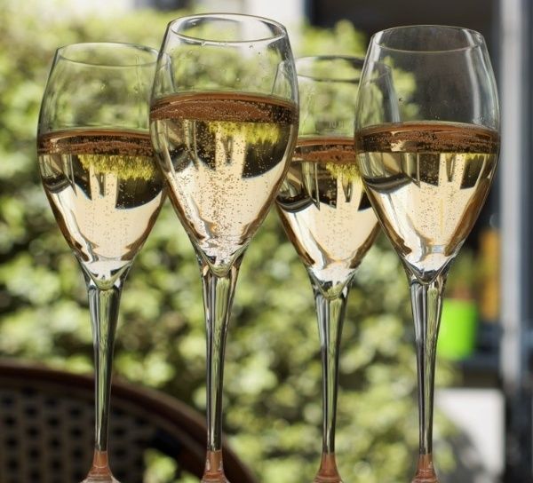 Four glasses of champagne are lined up on a table